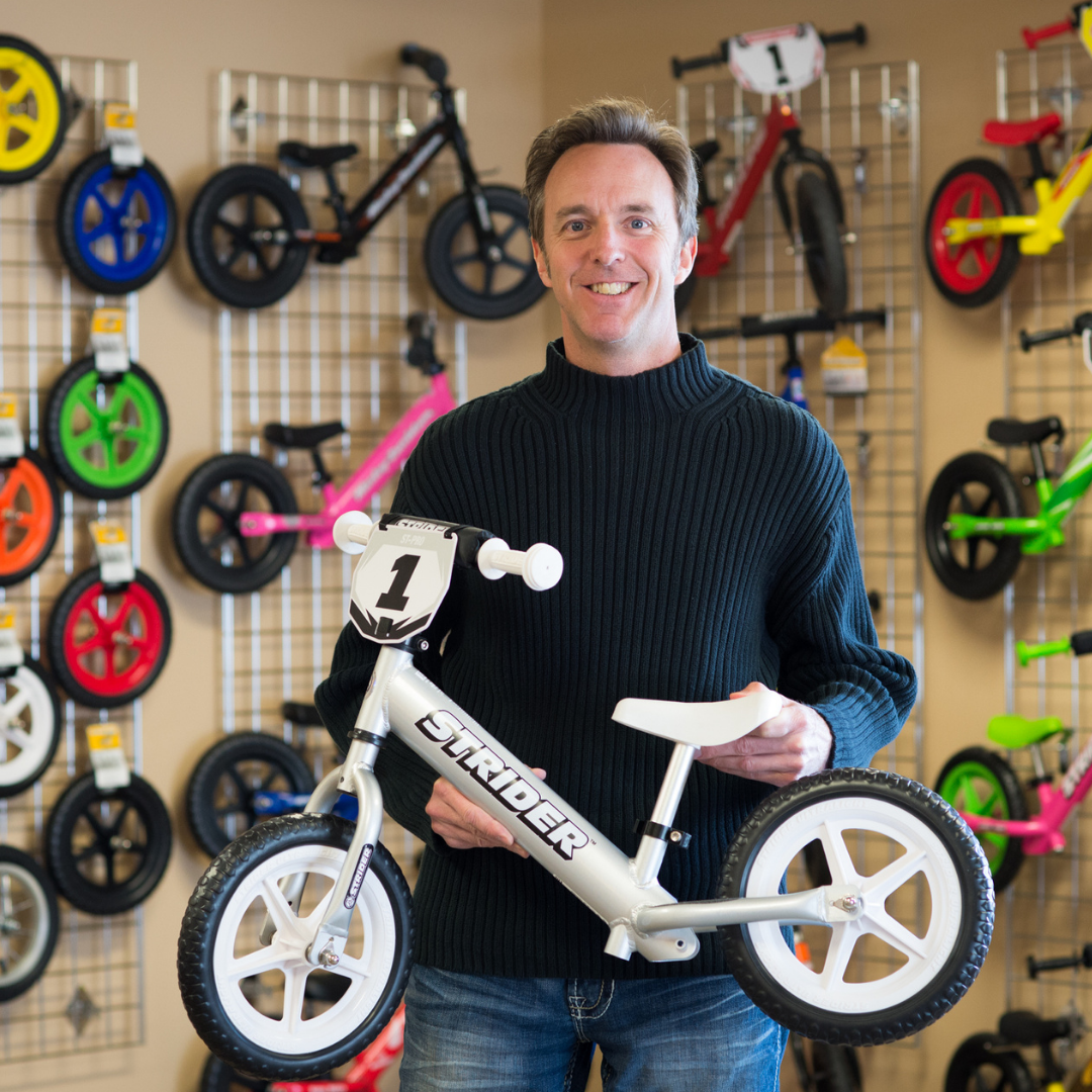 Strider founder Ryan McFarland posing with a12 inch Strider Pro balance bike