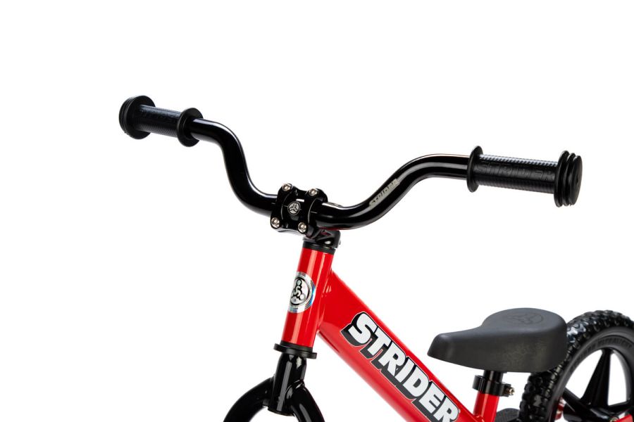 A studio shot of the Strider Aluminum High-Rise Wide handlebar on a red balance bike
