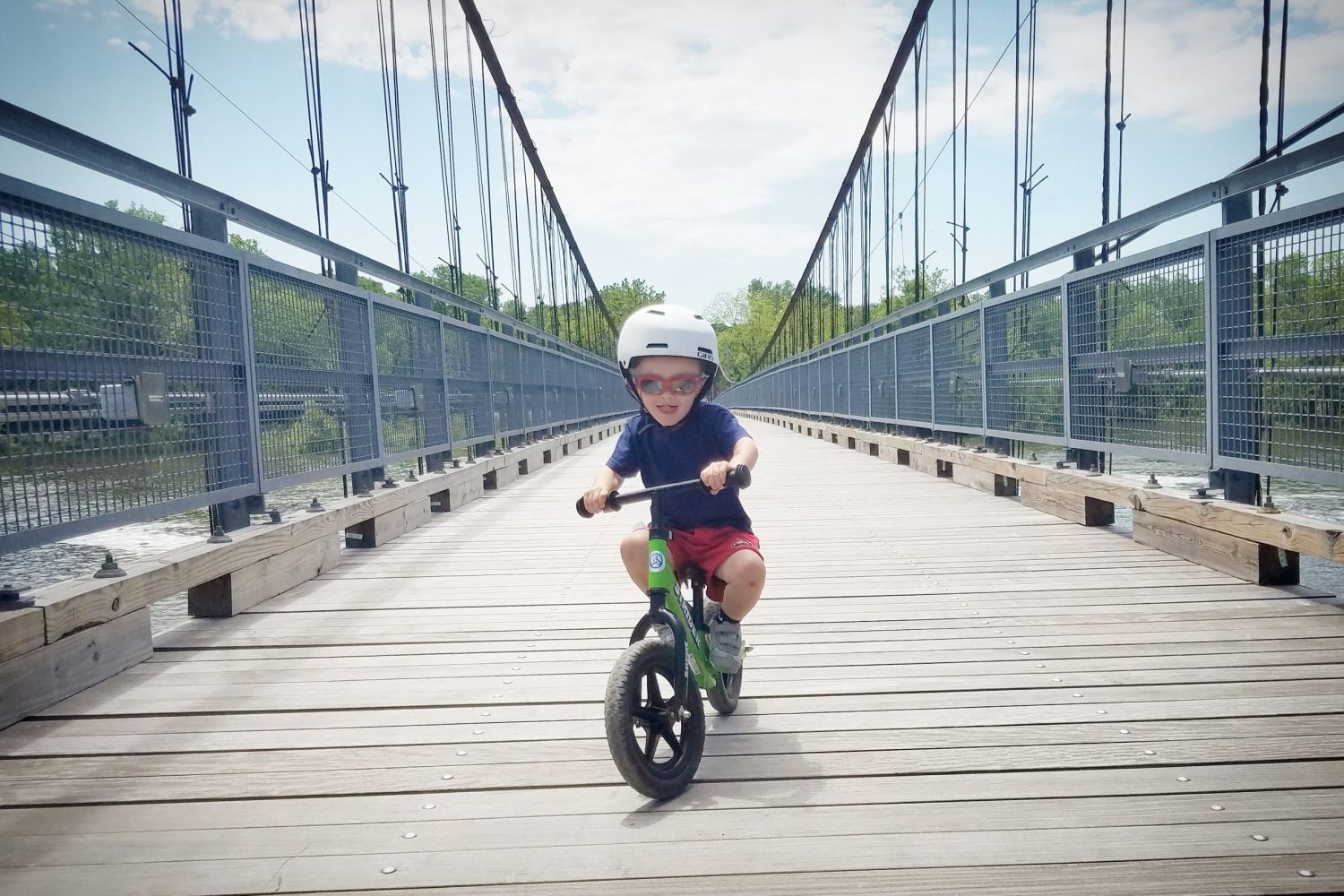 Child glides on Strider Balance Bike on a bridge