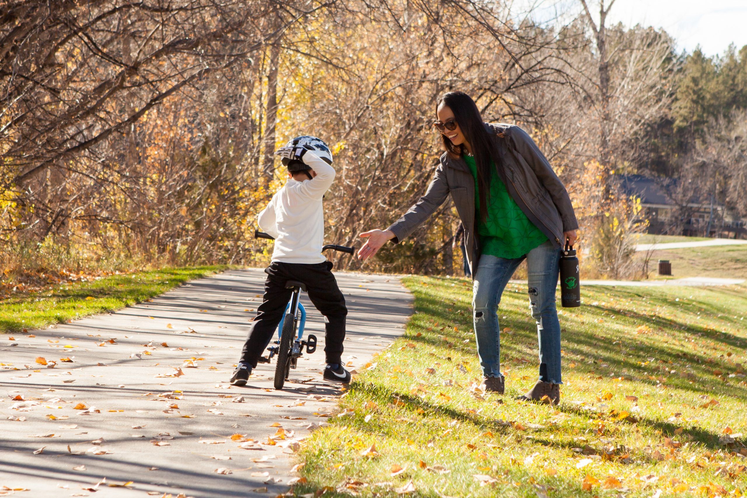 A mom gives her son a high five after he finds pedaling success on the Strider 14x Sport