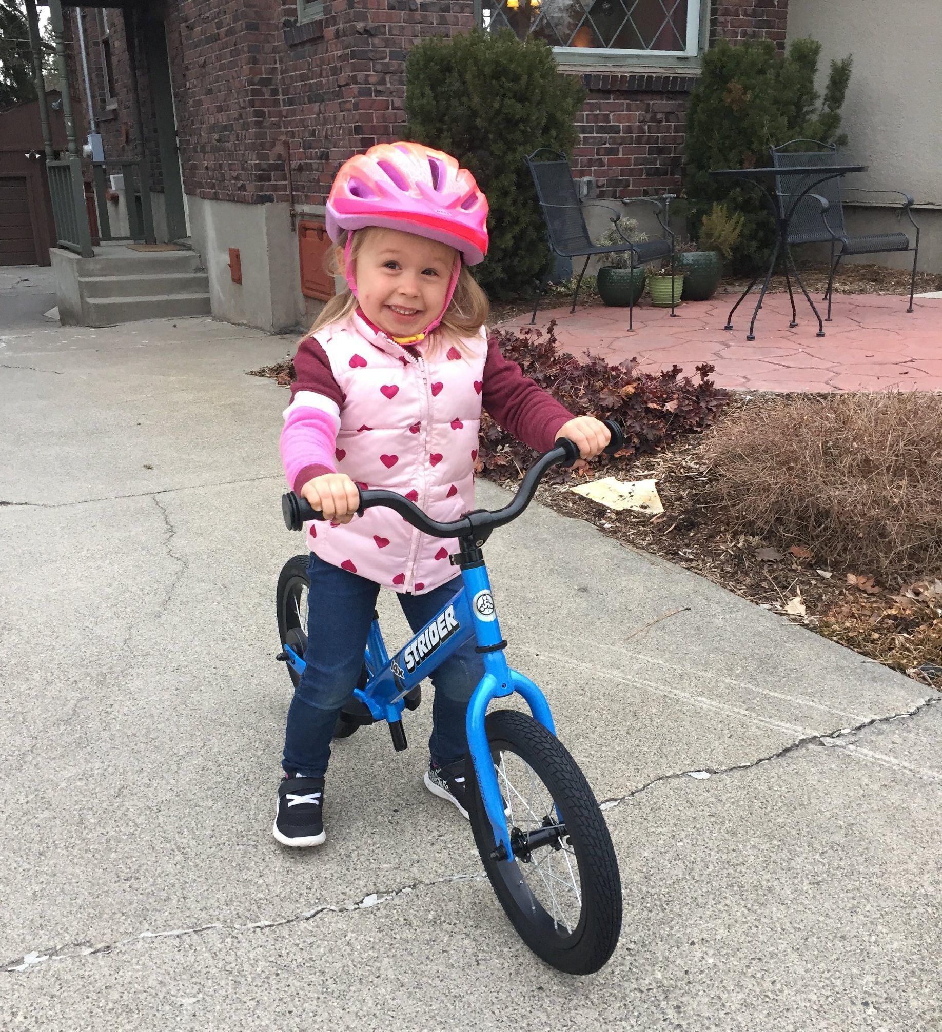 Girl with heart vest smiles with her new pedal bike 