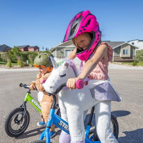 A girl in a unicorn costume on a Strider bike
