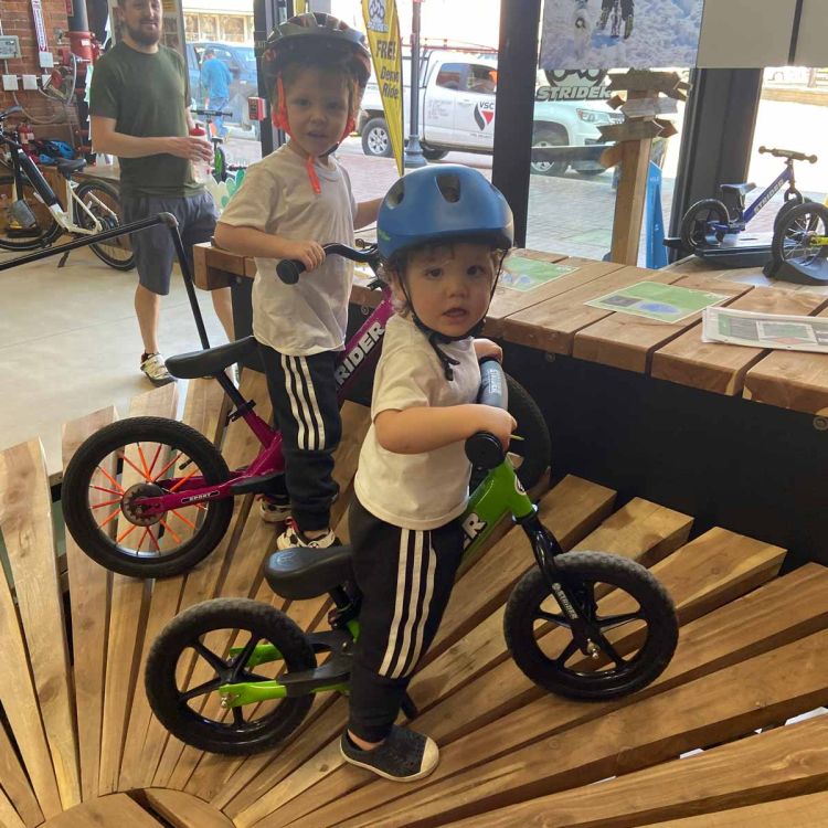 Two children ride Strider Bikes on a wooden bike ramp in Bentonville, Arkansas