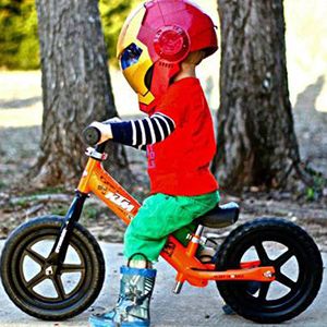 A child strides on their Strider Bike while wearing an Iron Man mask