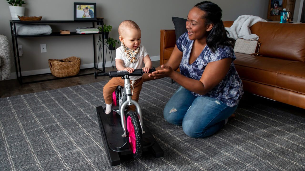 A baby on a silver Pro Rocking Bike plays with Mom