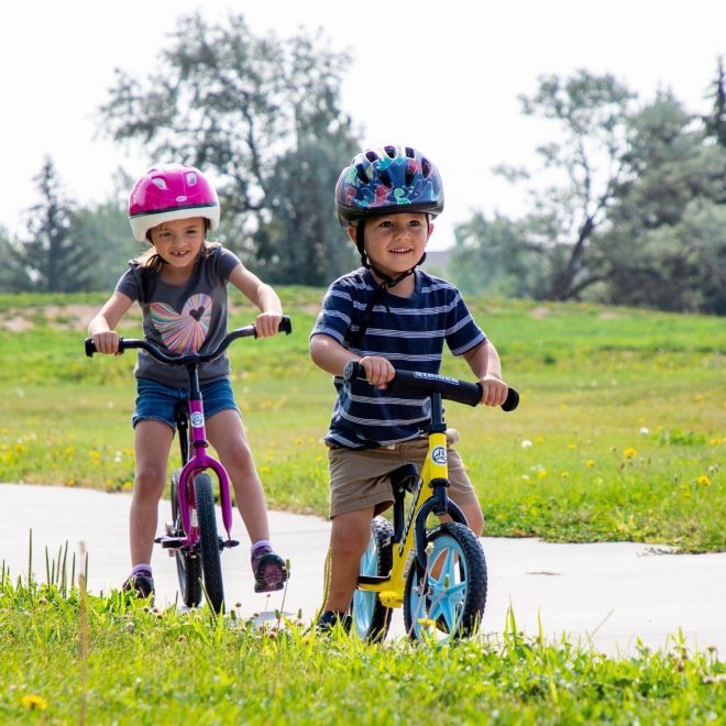 Boy and girl riding their Strider Bikes down the bike path