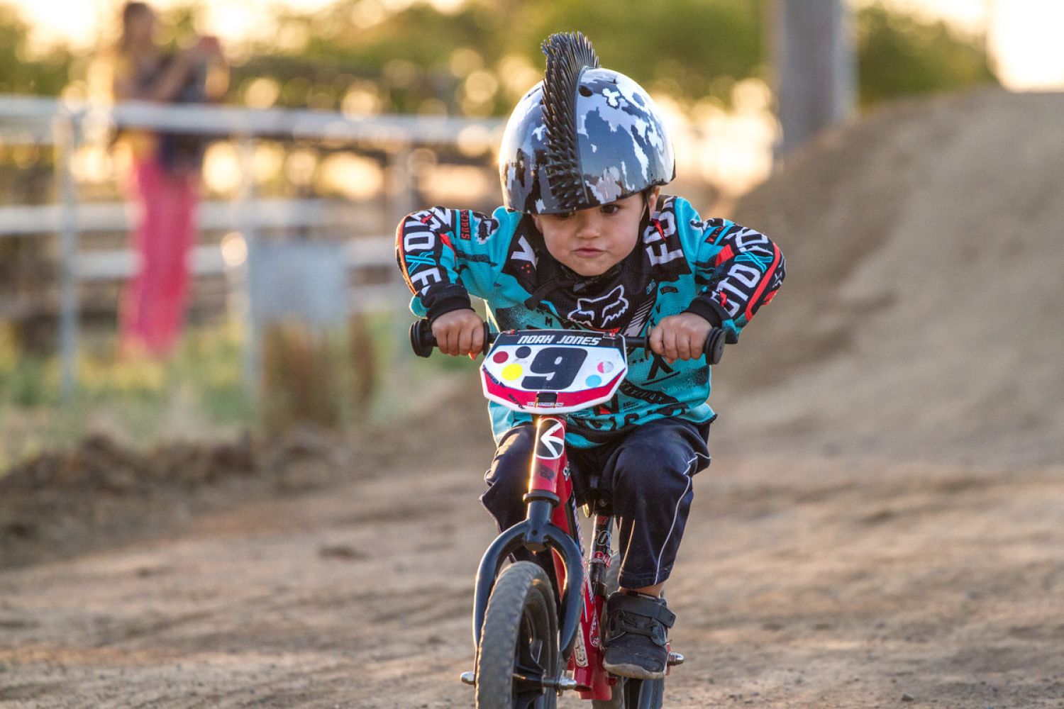 Boy in racing position riding on BMX track on red custom 12 Sport