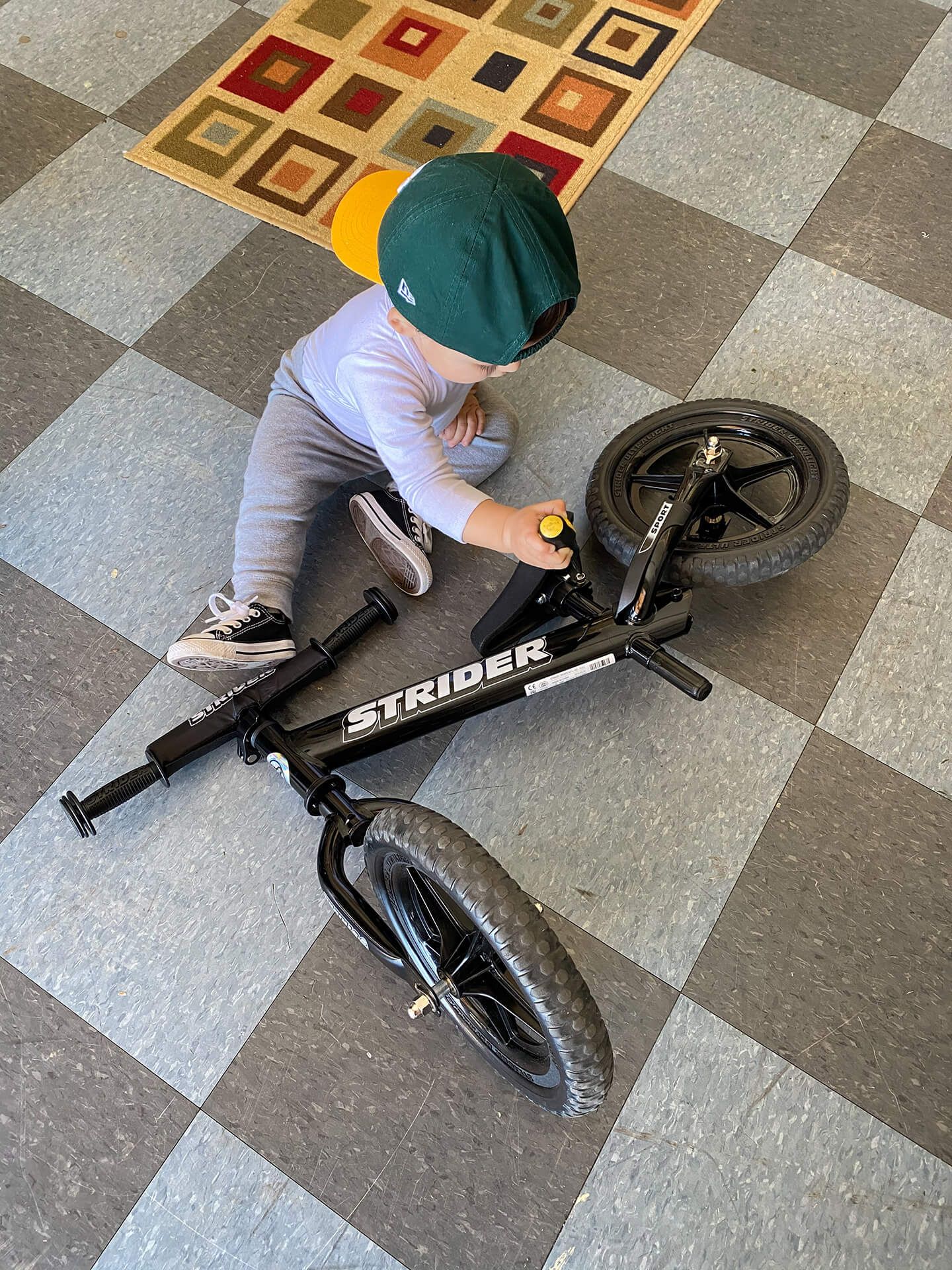 A child uses a screwdriver to "repair" a Strider Sport 12-inch balance bike