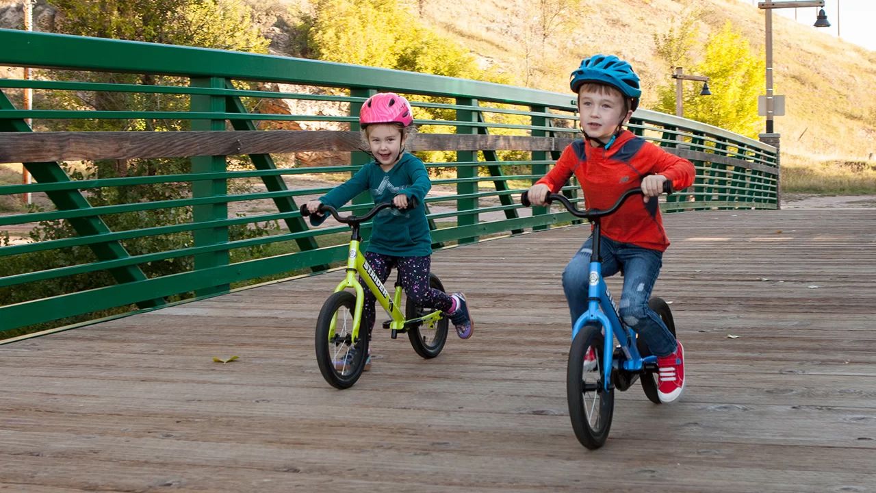 Boy and girl striding and pedaling Strider 14x bikes