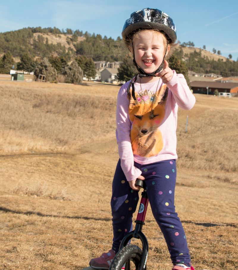 Gotcha! A girl points and laughs while holding onto a Strider Uno. Seriously, you couldn't ride that thing.