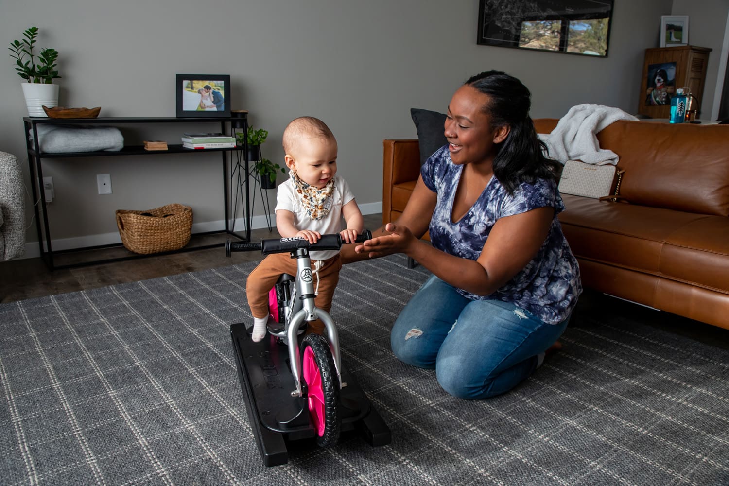 A mom and baby play on a silver Strider Pro Rocking Bike