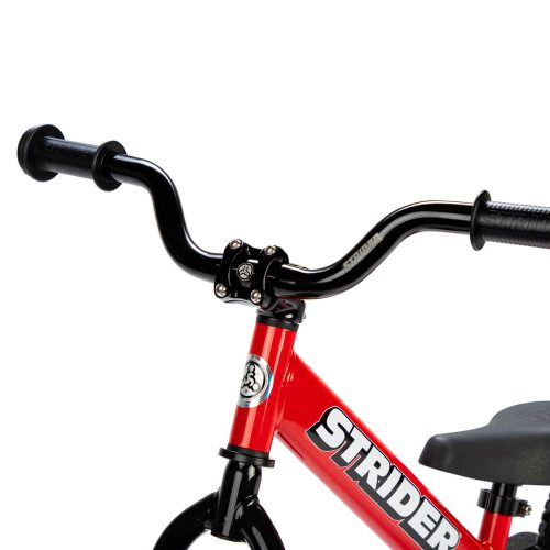 A studio shot of the Strider Aluminum High-Rise Wide handlebar on a red balance bike