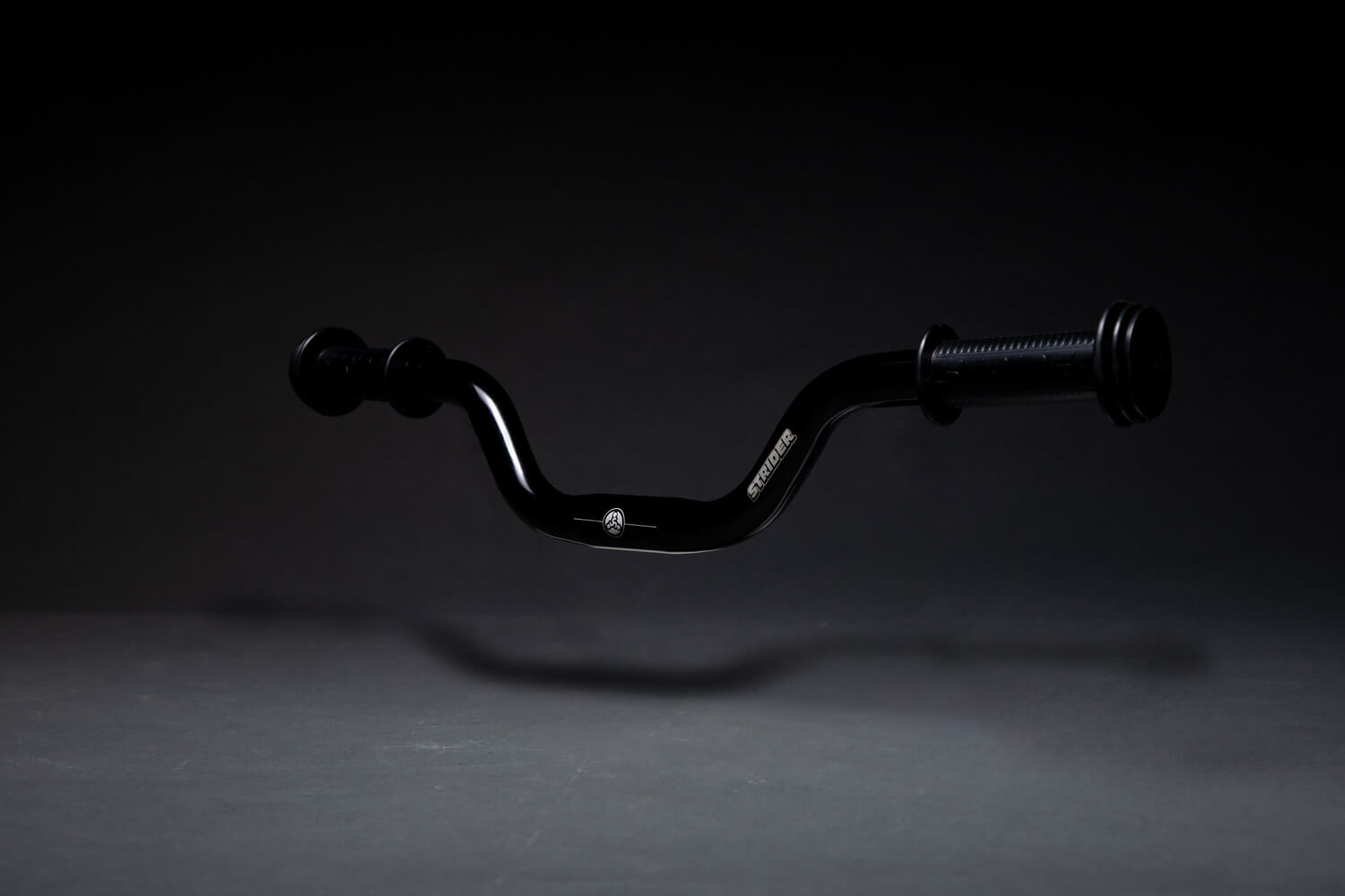 A studio shot of the Strider Aluminum High-Rise Wide Handlebar free-floating against a black backdrop
