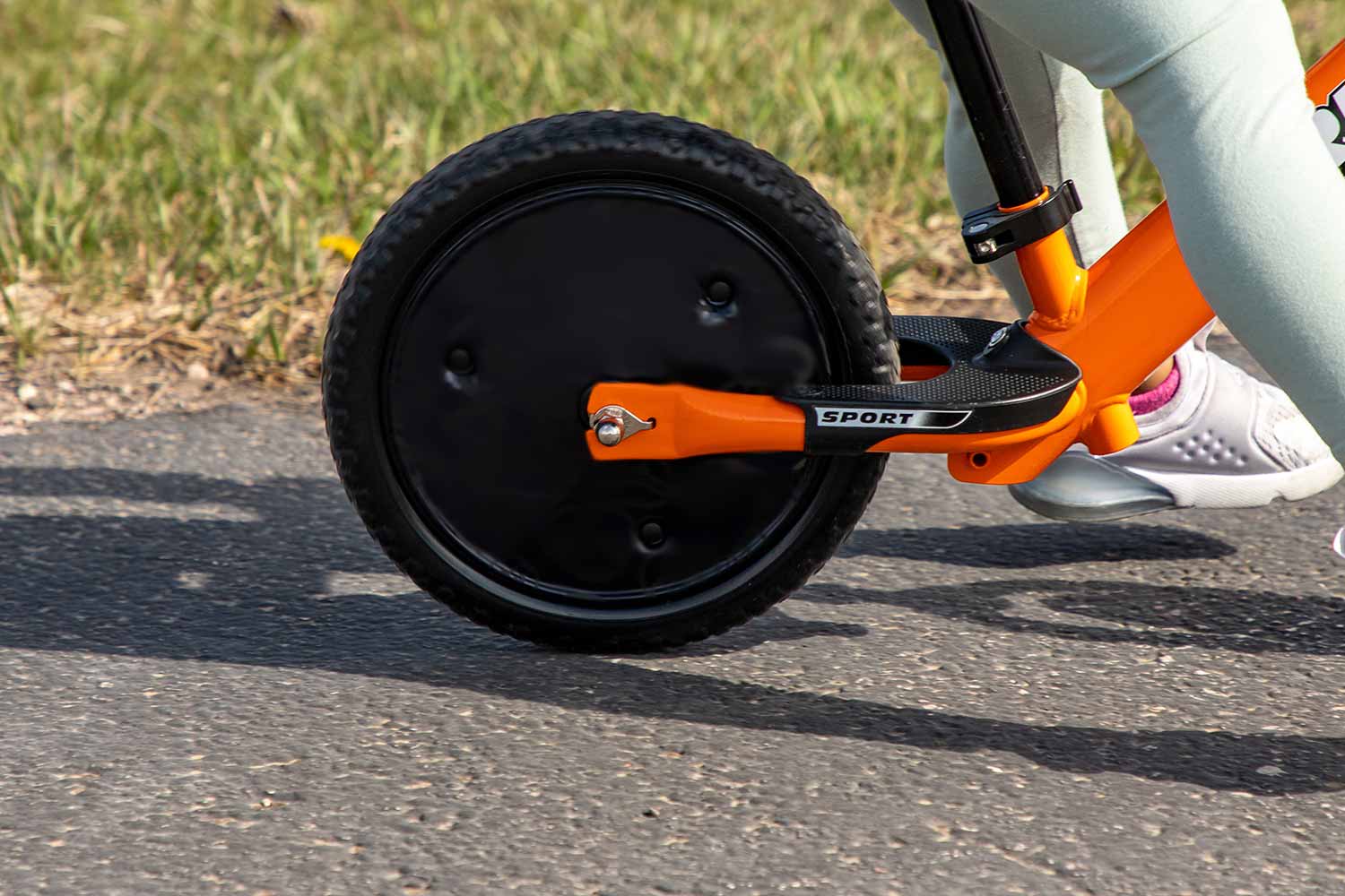 A close-up detail of Strider Disc Wheel covers installed on an orange Strider 12 Sport bike